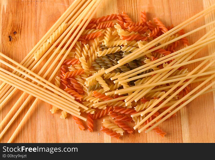 Raw colour pasta background on yellow wooden cook-table. Raw colour pasta background on yellow wooden cook-table