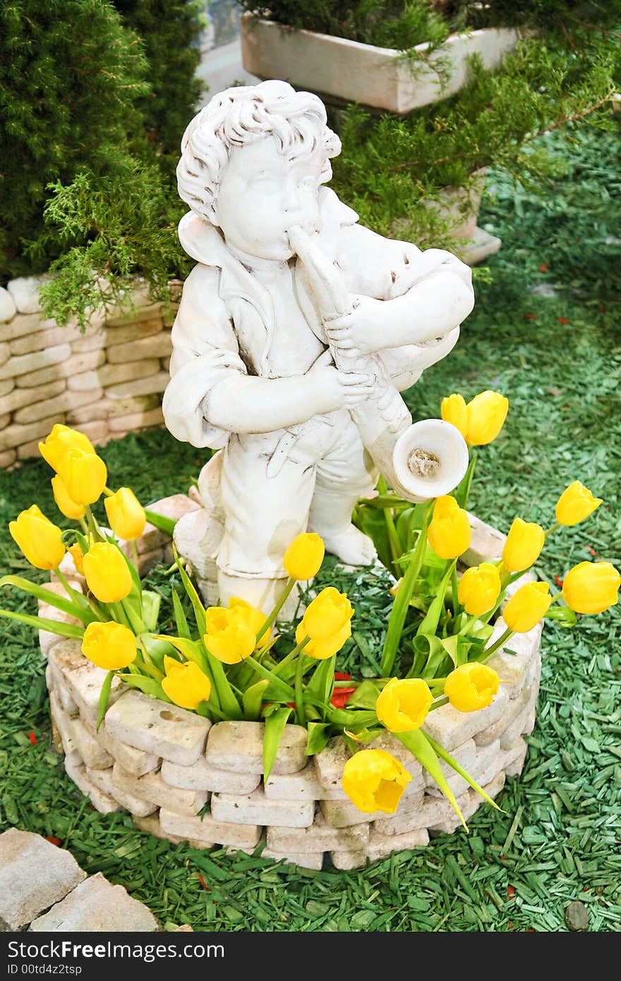 Statue of a boy with saxaphone in flowerbed with tulips in the park. Statue of a boy with saxaphone in flowerbed with tulips in the park