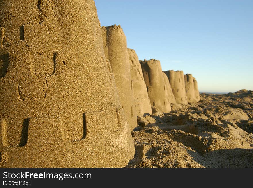 Sandcastles at the beach illustrate risk from incoming tide. Sandcastles at the beach illustrate risk from incoming tide