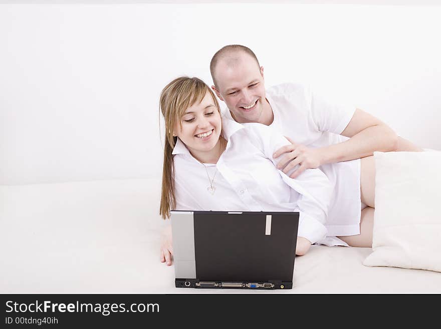 Happy couple with laptop on a couch. Relax at home.