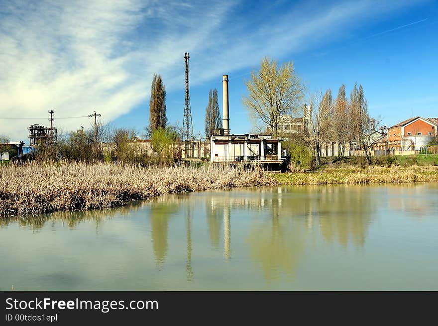 A view with a industrial facility and water reflection