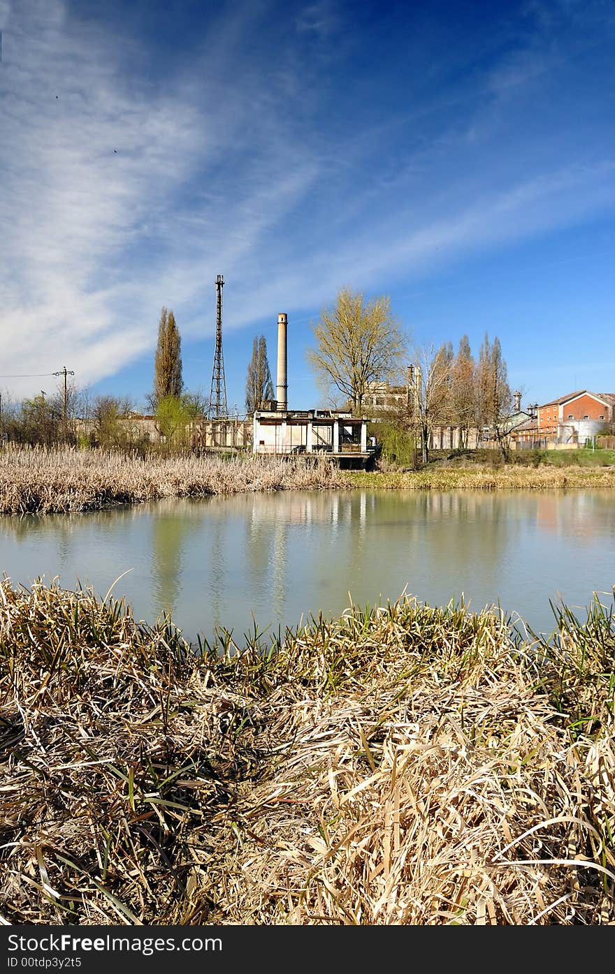 A view with an abandoned industrial facility and water reflection