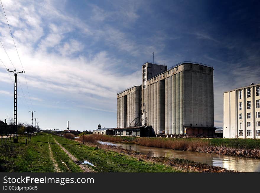 A view with a concrete silo along a river. A view with a concrete silo along a river