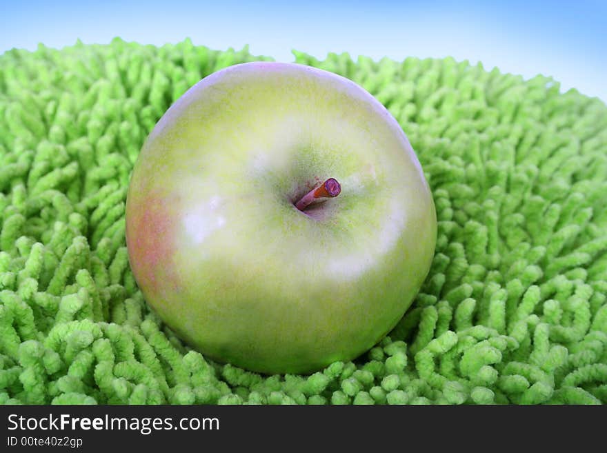 Green juicy apple on the artificial grass