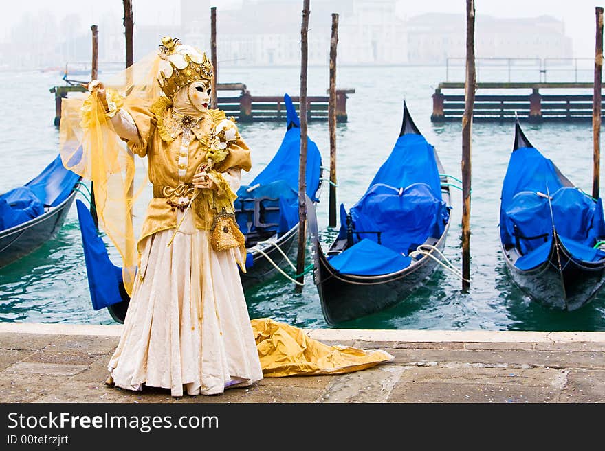 A lady wearing a wonderful gold costume in front of gondolas. A lady wearing a wonderful gold costume in front of gondolas