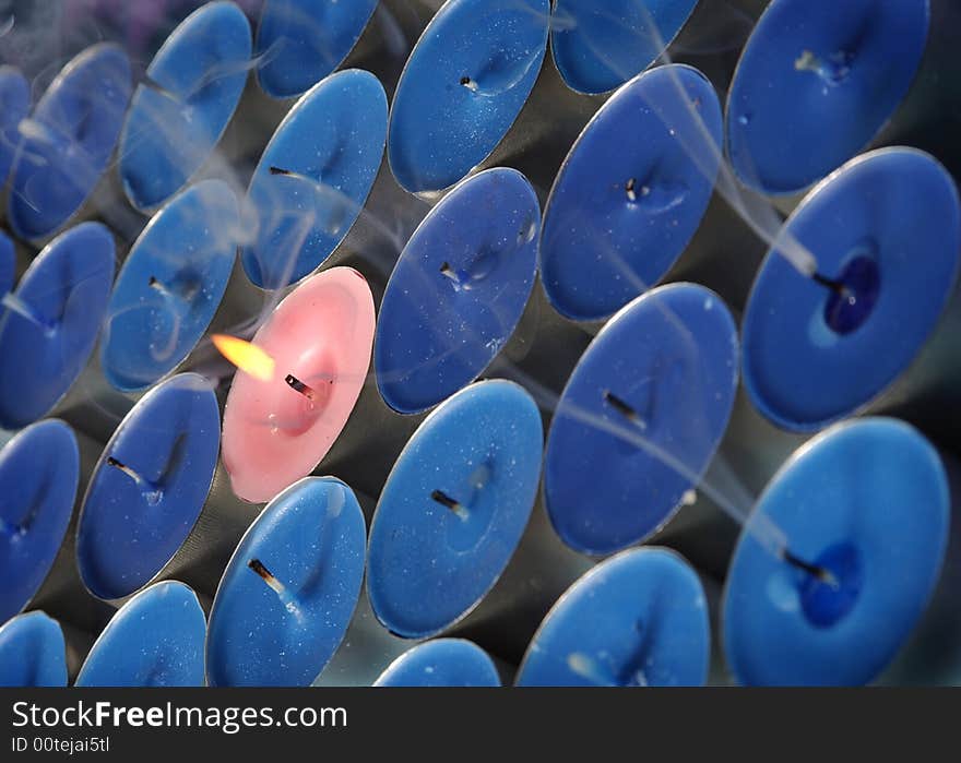 Pink candle surrounded by blue candles conceptual