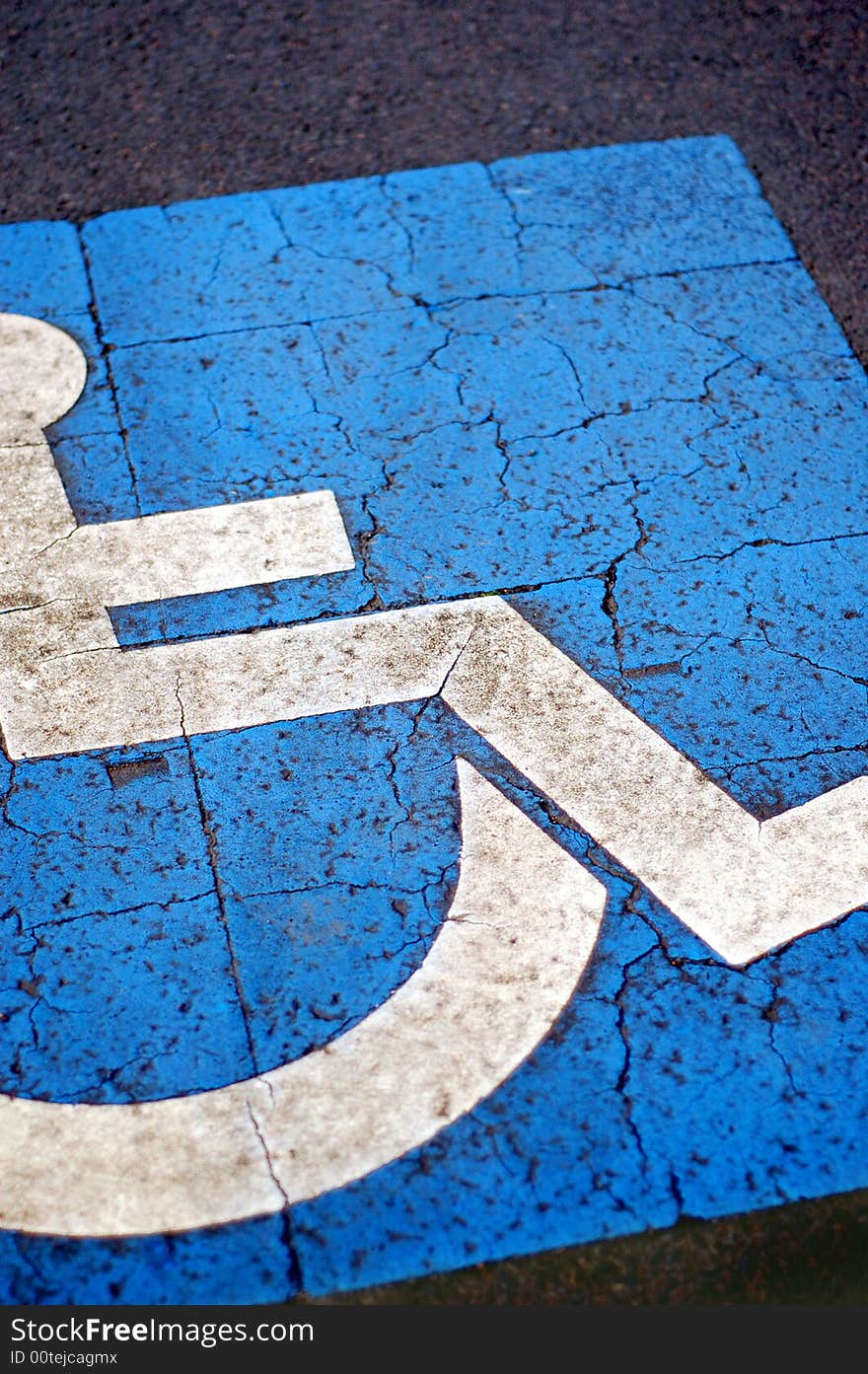 International symbol for handicapped parking, blue paint on asphalt. International symbol for handicapped parking, blue paint on asphalt