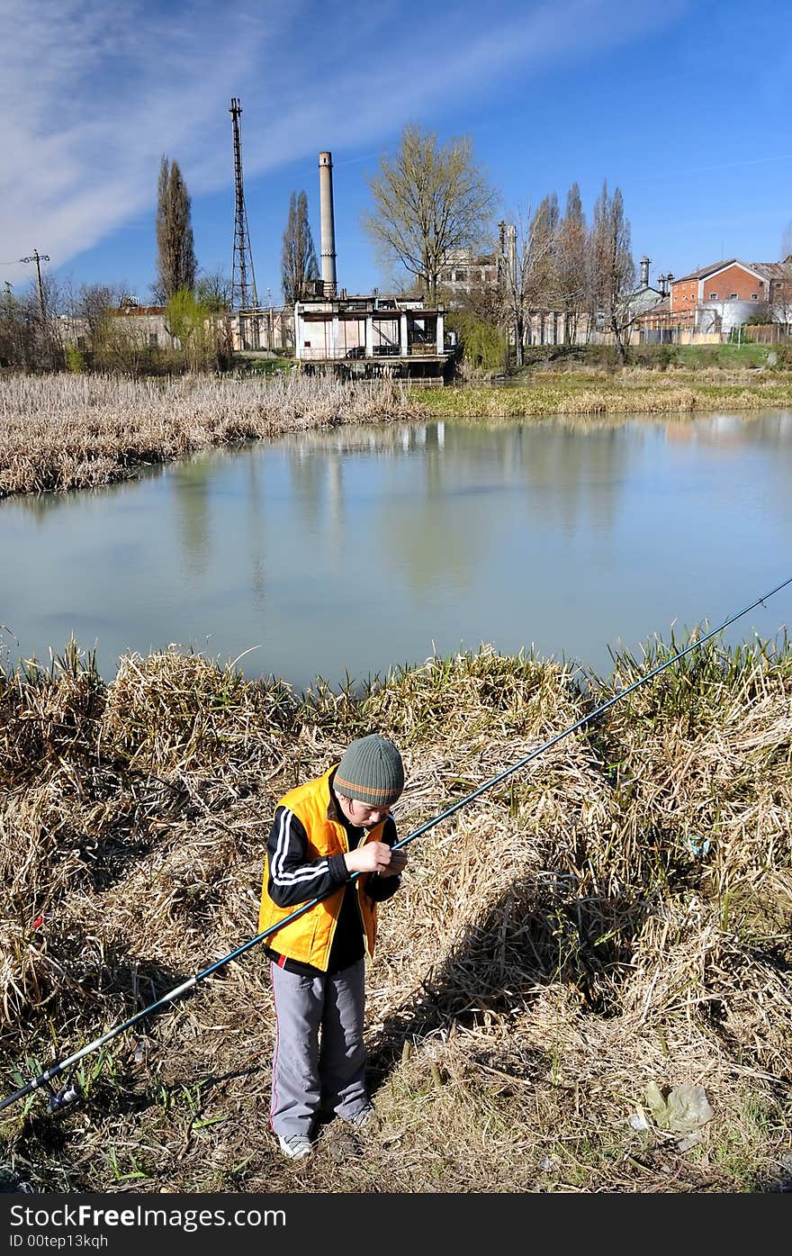 Little boy fishing in an industrial waste waters.