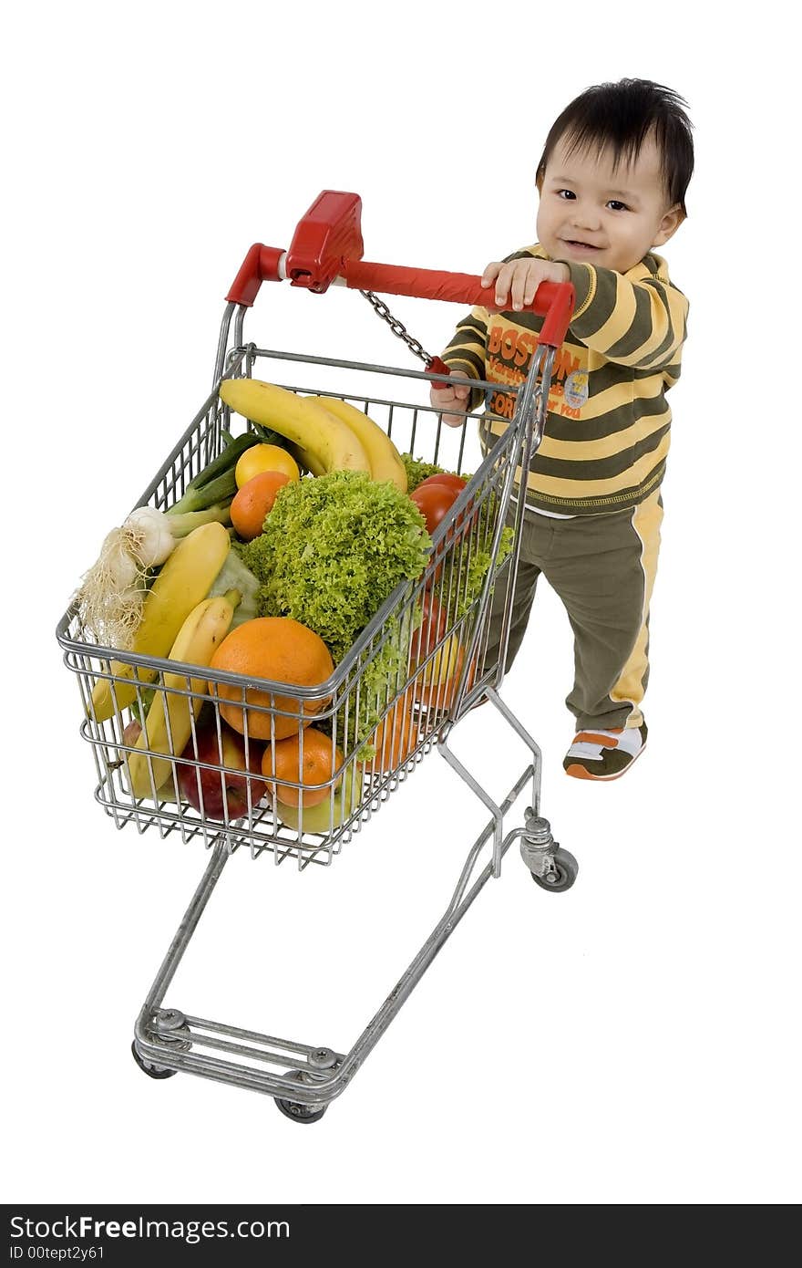 Baby pushes a shopping cart with fruits and vegetables before a white background. Baby pushes a shopping cart with fruits and vegetables before a white background