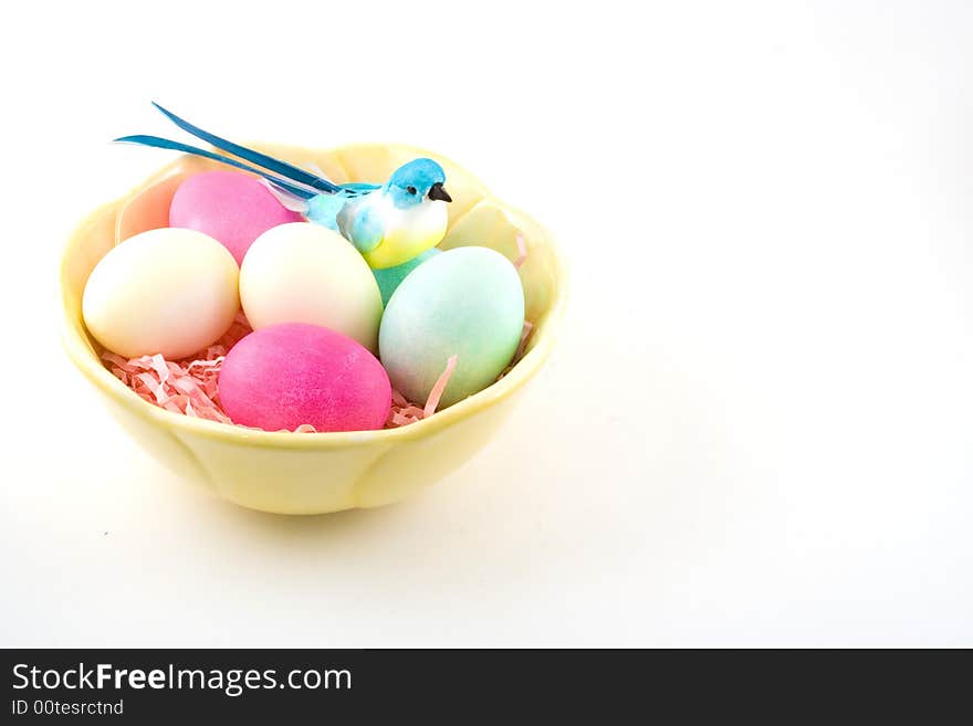 Hardboiled and dyed Easter eggs in a bowl with a decorative blue bird sitting to one side. Hardboiled and dyed Easter eggs in a bowl with a decorative blue bird sitting to one side.