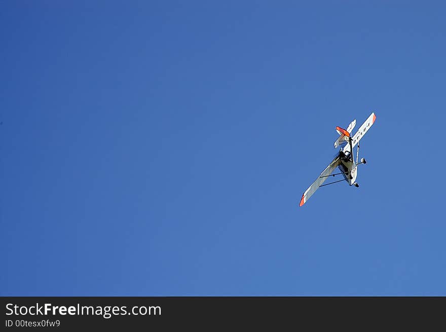 Sports ultralight airplane in turn left in the blue sky. Sports ultralight airplane in turn left in the blue sky