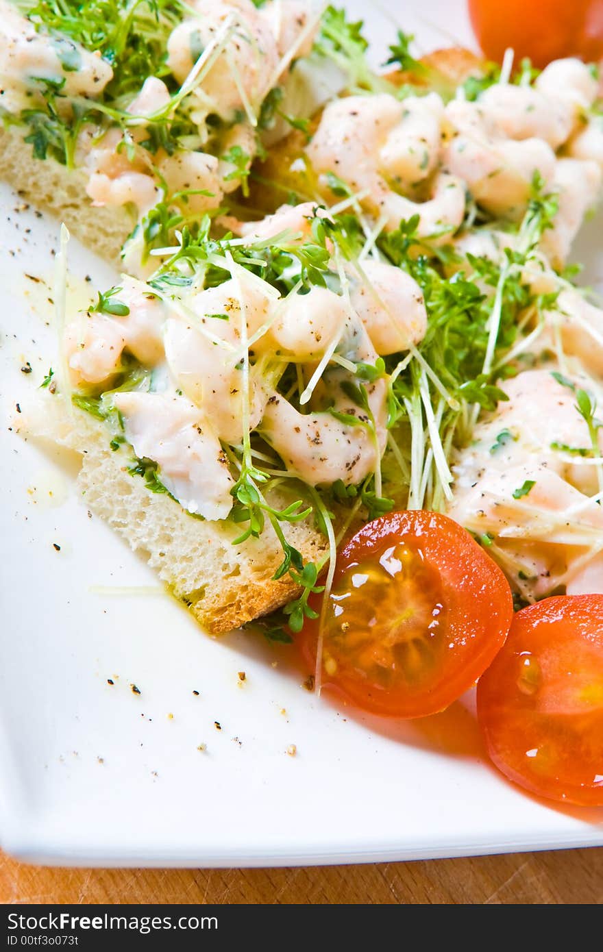 Sliced prawn and cress sandwich with tomatoes on a white plate