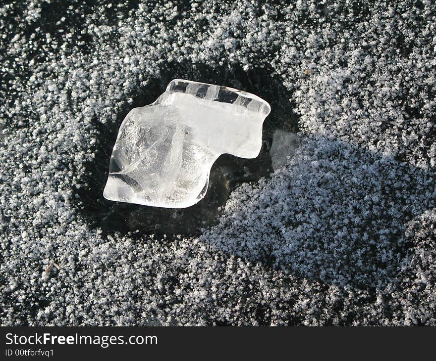 Translucent peace of melted white ice on snow background