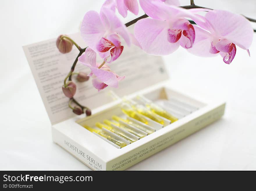 Serum Ampules in the box with pink orchid around. Serum Ampules in the box with pink orchid around