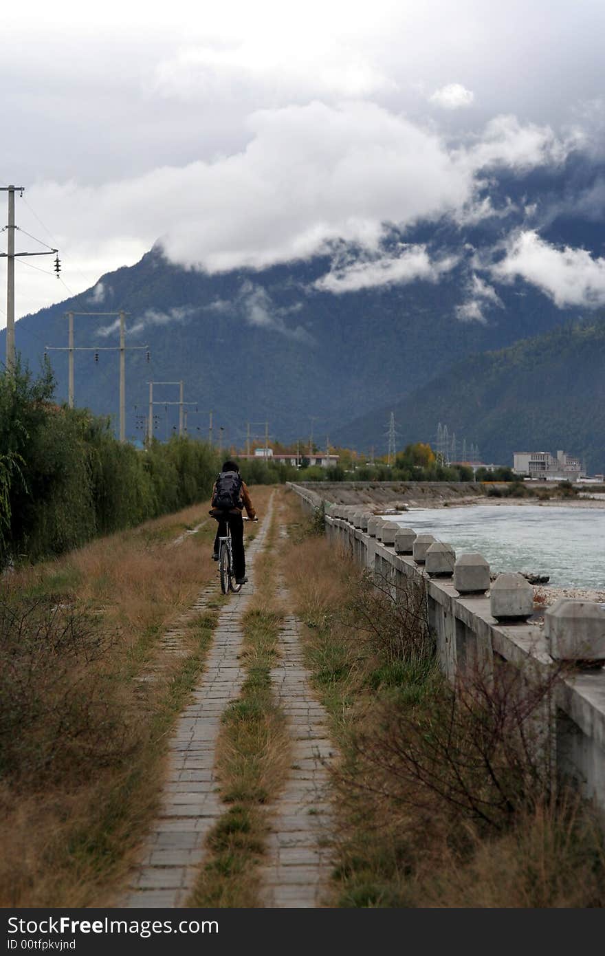 A man cycling by the riverside in deep valley - Tibet-china. A man cycling by the riverside in deep valley - Tibet-china.