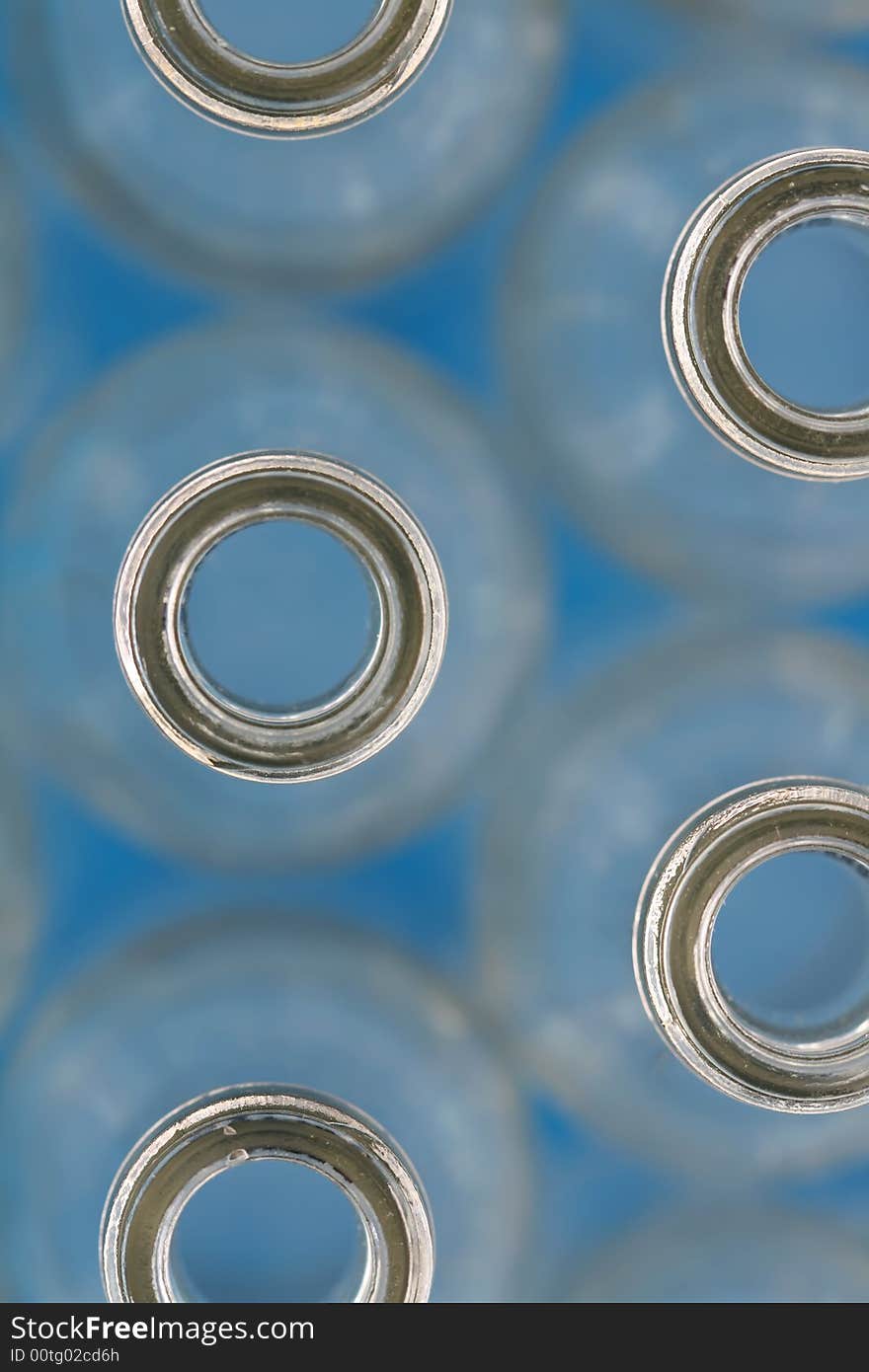 Close up of rows of bottles taken from the top, on a blue background