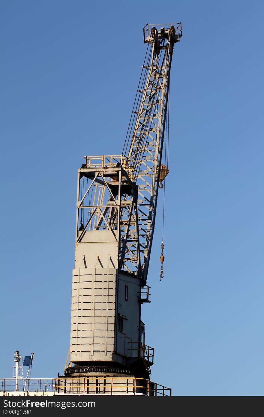 A harbour crane silhouette against the blue sky