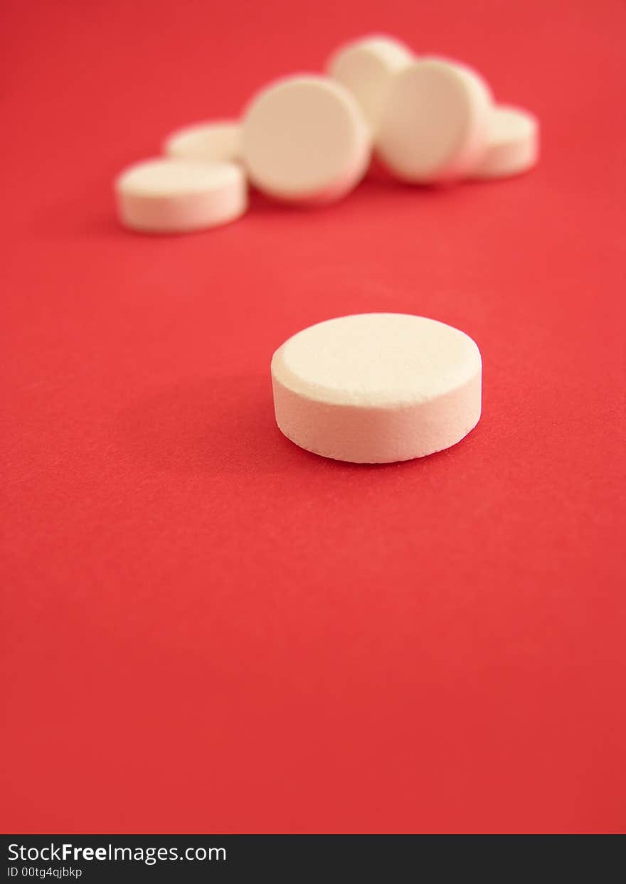 White tablets on the red background.
Focus on the first plane