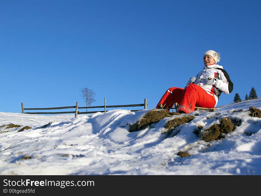 The sports girl on sledge climbs down a mountain