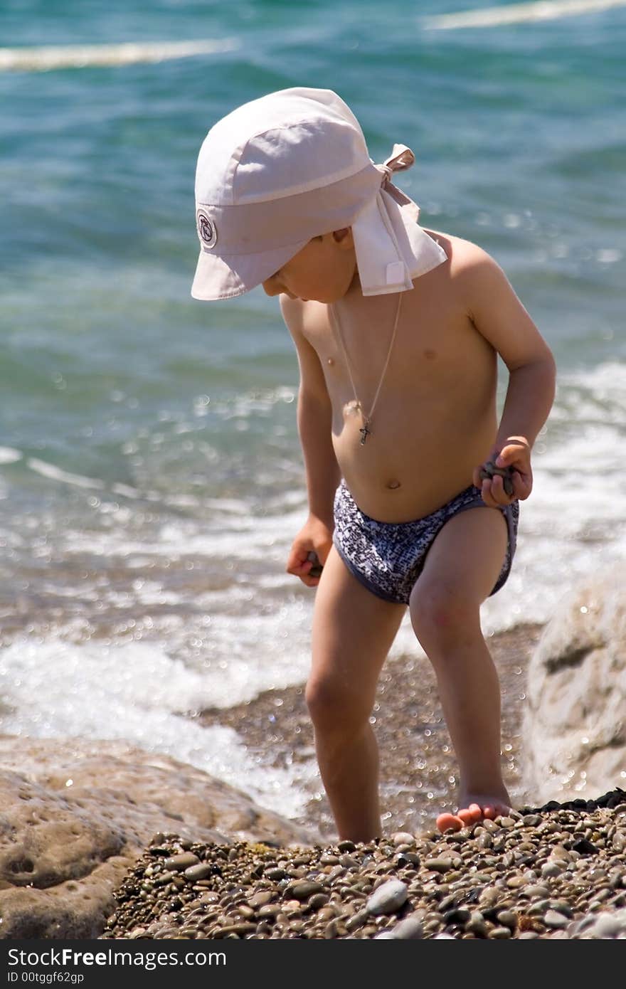 A little boy plays at a large stone ashore black sea. A little boy plays at a large stone ashore black sea