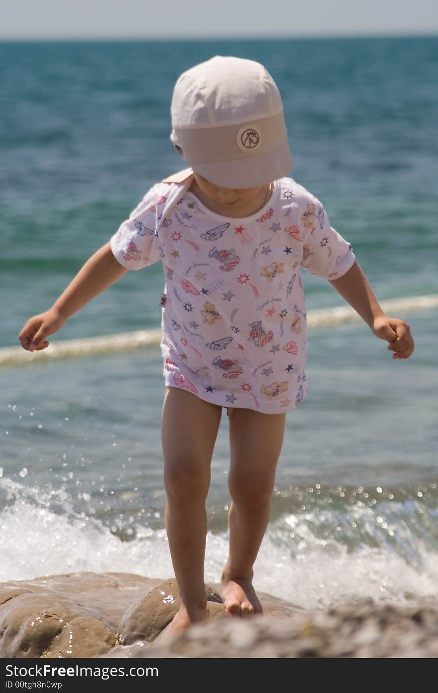 A little boy plays at a large stone ashore black sea. A little boy plays at a large stone ashore black sea