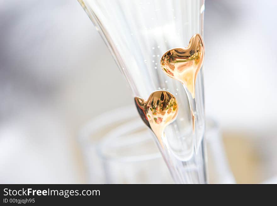 Two golden hearts on the glass of champagne