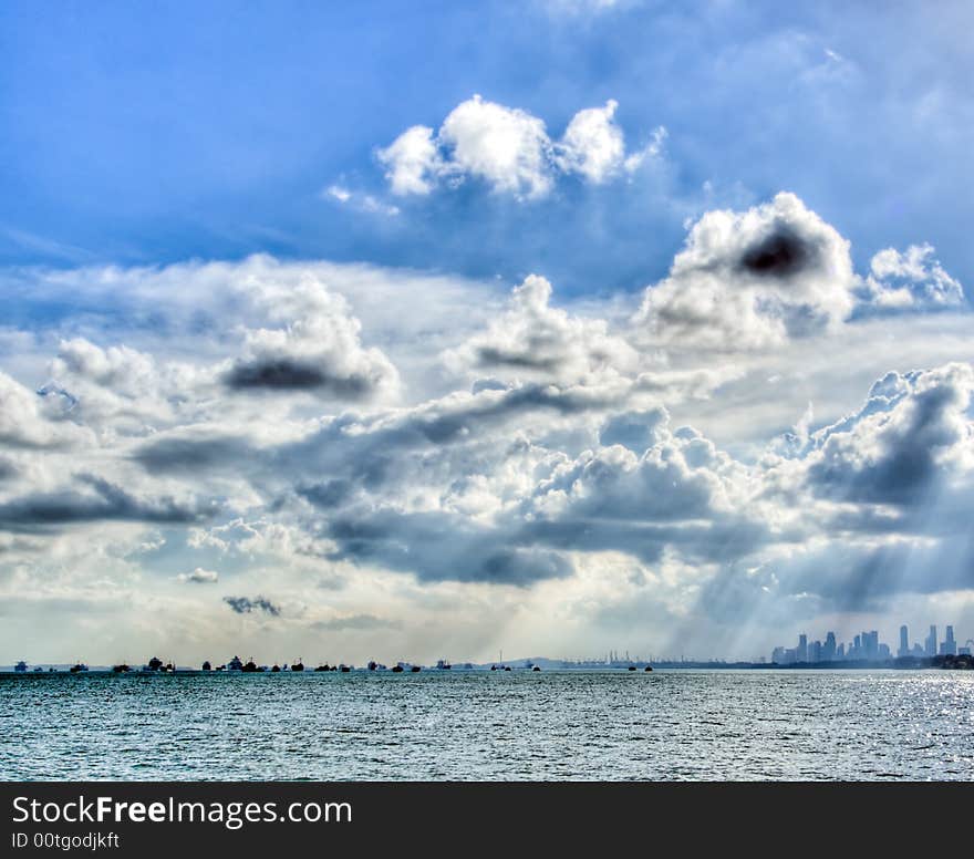 Clouds over the port of Singapore in bright intense afternoon sun. Clouds over the port of Singapore in bright intense afternoon sun