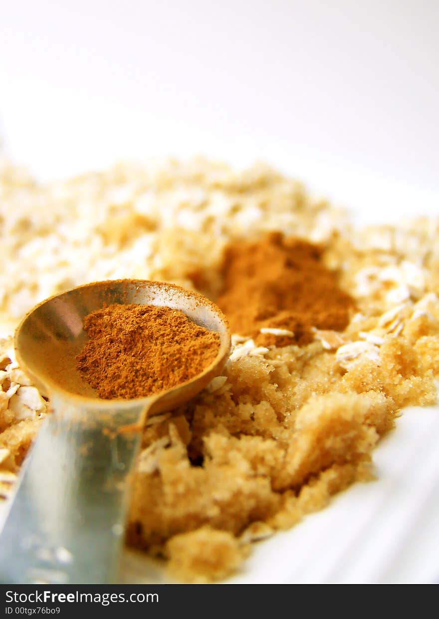 Image of cinnamon in a metal measuring spoon, with brown sugar and oats.  Room for text or other material remains at the top of the image. Vertical orientation. Image of cinnamon in a metal measuring spoon, with brown sugar and oats.  Room for text or other material remains at the top of the image. Vertical orientation.