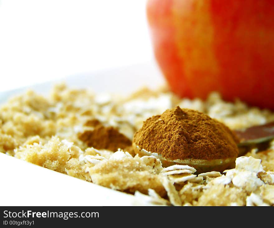 Image of a heaping spoonful of cinnamon, with brown sugar and oats surrounding and a bright red apple in the backgroujnd.  Room for text remains in top left hand quarter of the image.  Horizontal orientation. Image of a heaping spoonful of cinnamon, with brown sugar and oats surrounding and a bright red apple in the backgroujnd.  Room for text remains in top left hand quarter of the image.  Horizontal orientation.