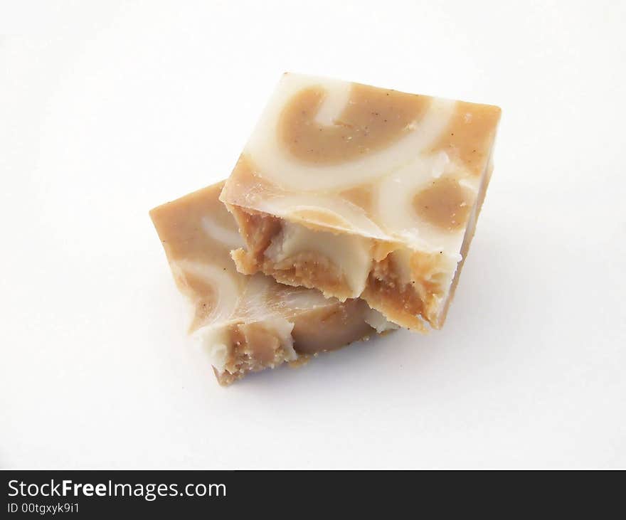 A bar of homemade, handcut cinnamon soap broken into two pieces, on a white background.  Horizontal orientation. A bar of homemade, handcut cinnamon soap broken into two pieces, on a white background.  Horizontal orientation.