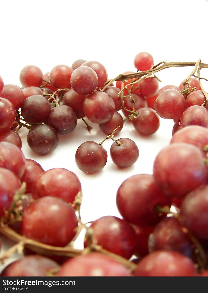 Image of red grapes arranged in a ring surrounding two that are joined together.  White background.  Vertical orientation. Image of red grapes arranged in a ring surrounding two that are joined together.  White background.  Vertical orientation.