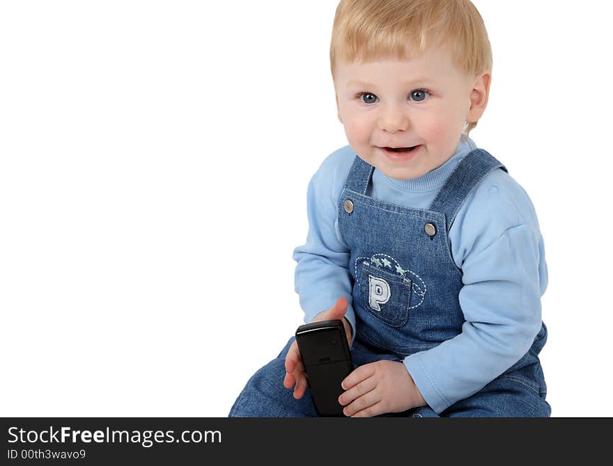 The small beautiful boy laughs and sits at a mobile phone in hands. The small beautiful boy laughs and sits at a mobile phone in hands