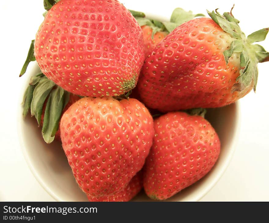 Close up image of a small white bowl with four large bright red strawberries, on white background. Close up image of a small white bowl with four large bright red strawberries, on white background.