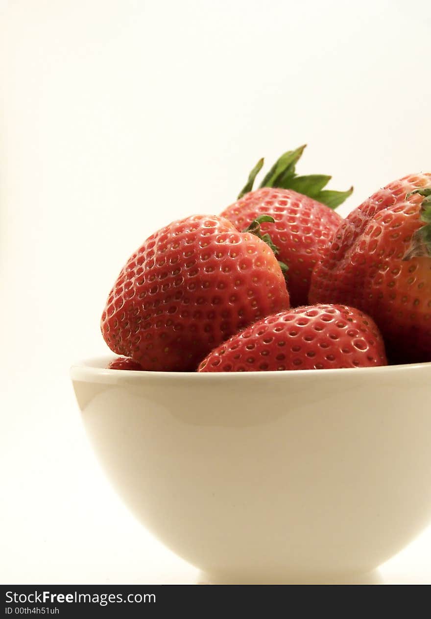 Close up image of four large red strawberries in a small white bowl, on white background. Close up image of four large red strawberries in a small white bowl, on white background.