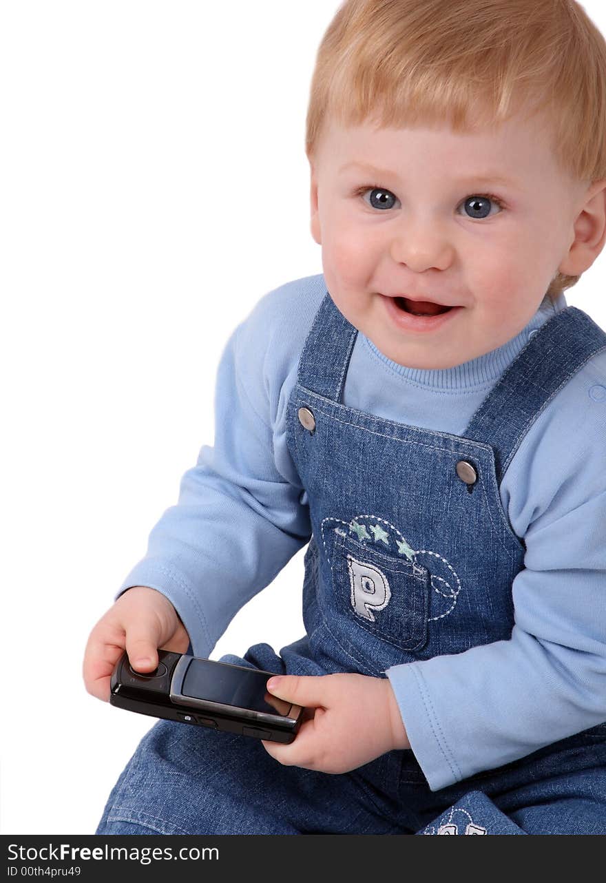 The small beautiful boy laughs and sits at a mobile phone in hands. The small beautiful boy laughs and sits at a mobile phone in hands