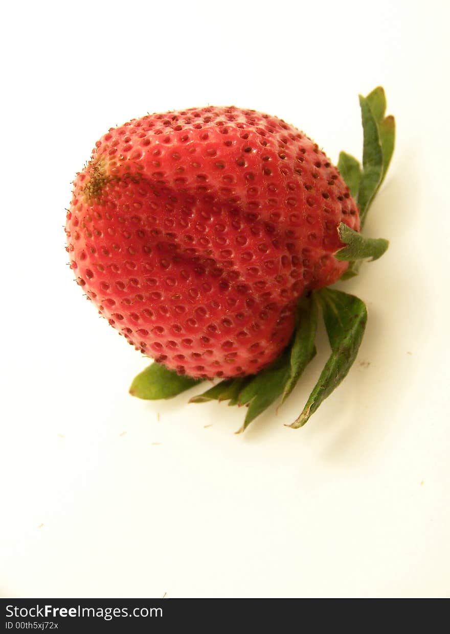 Image of a large, bright red strawberry turned upside down.  Angled shot with vertical orientation and white background. Image of a large, bright red strawberry turned upside down.  Angled shot with vertical orientation and white background.