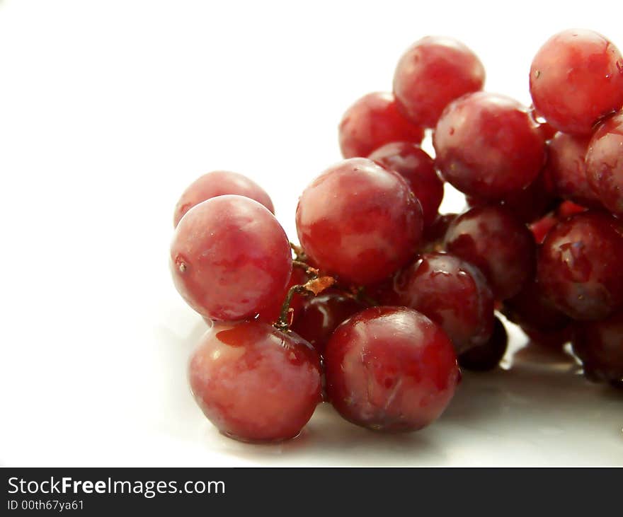 Image of wet red grapes, on white background.  Horizontal orientation. Image of wet red grapes, on white background.  Horizontal orientation.