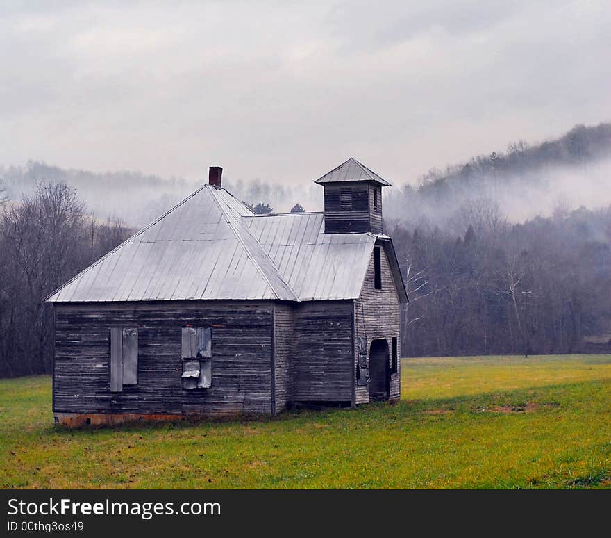 An old tin-roofed schoolhouse, a fog rising above the bare trees in the hills beyond. An old tin-roofed schoolhouse, a fog rising above the bare trees in the hills beyond.