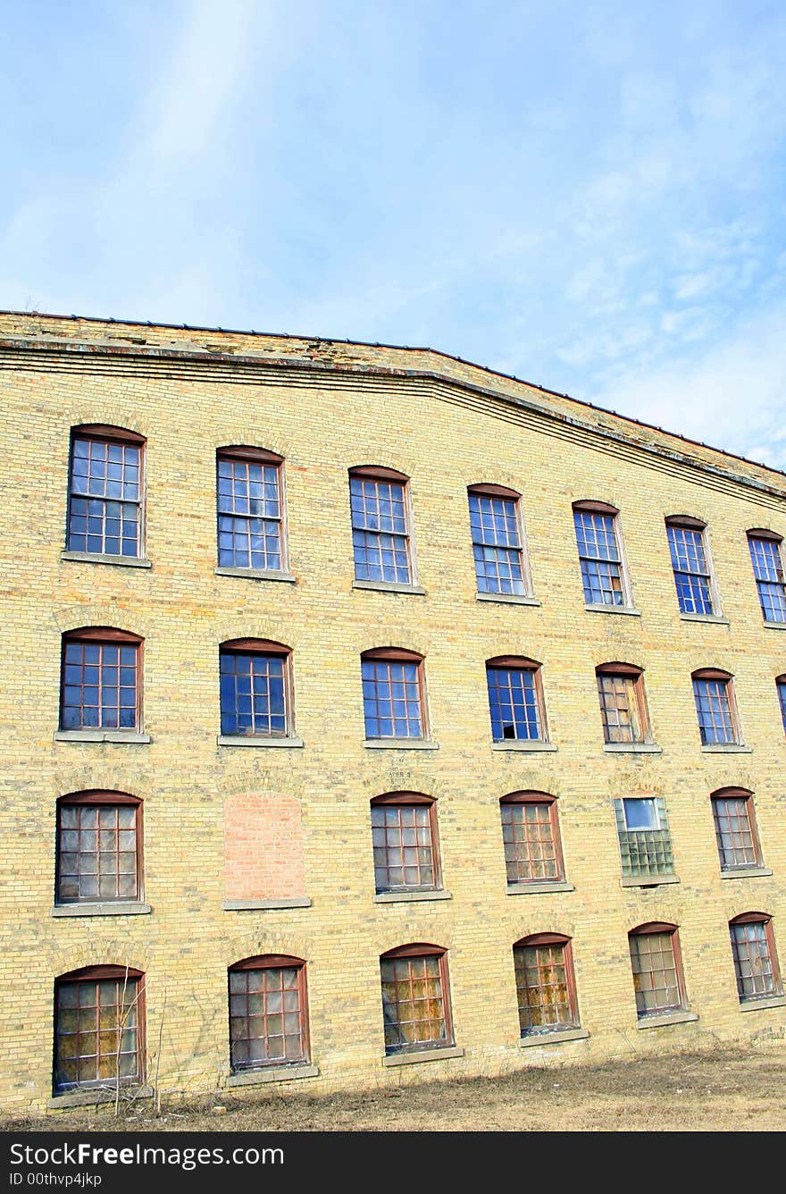 An old abandoned paper mill from the 1800s, under a blue sky. An old abandoned paper mill from the 1800s, under a blue sky.