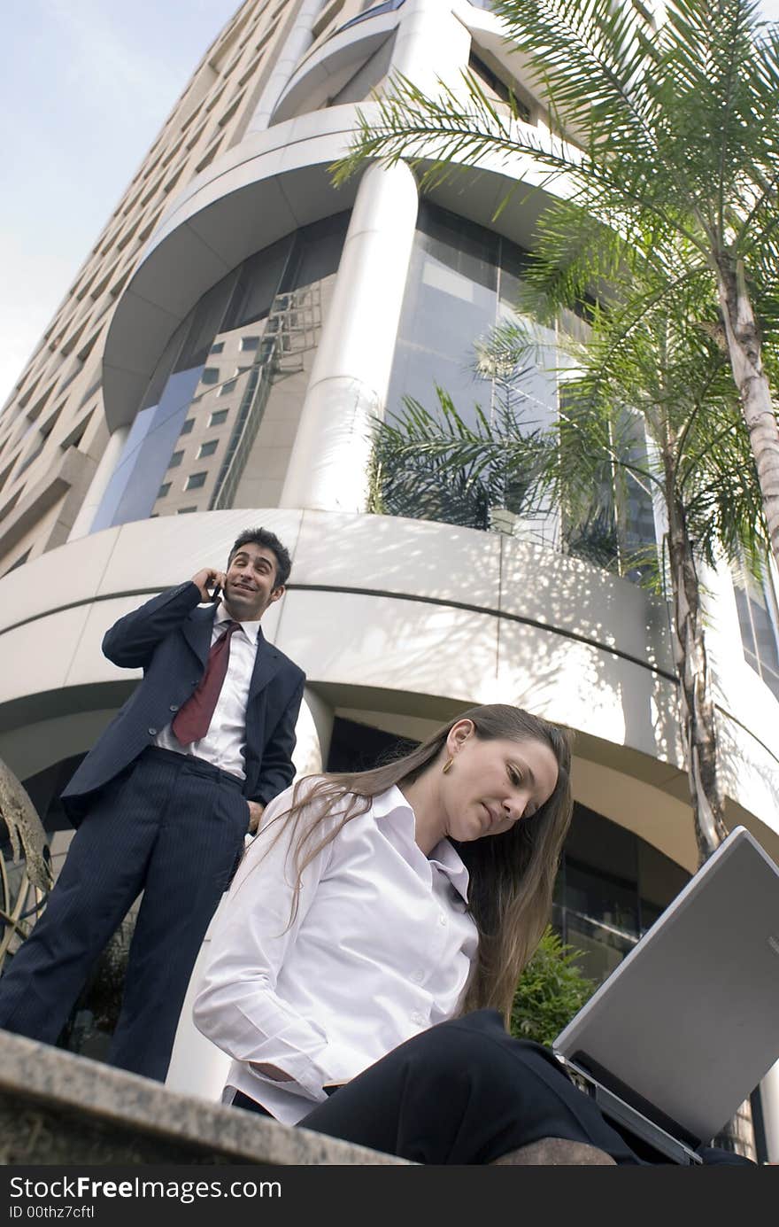 Man and woman in business attire working together outdoors. Man and woman in business attire working together outdoors