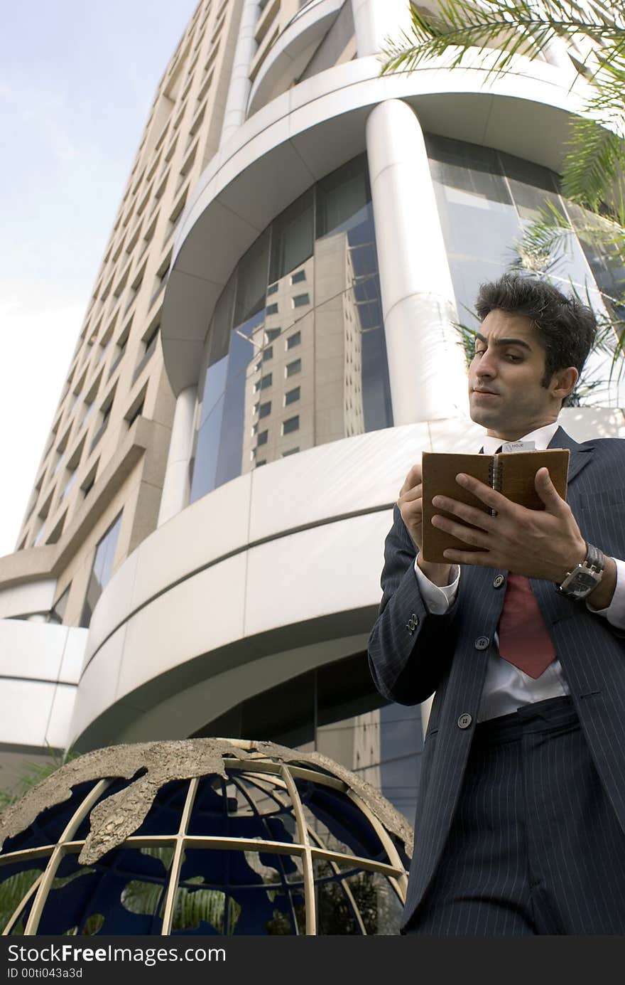 Man in a business suit skeptically writing in his day planner. Man in a business suit skeptically writing in his day planner