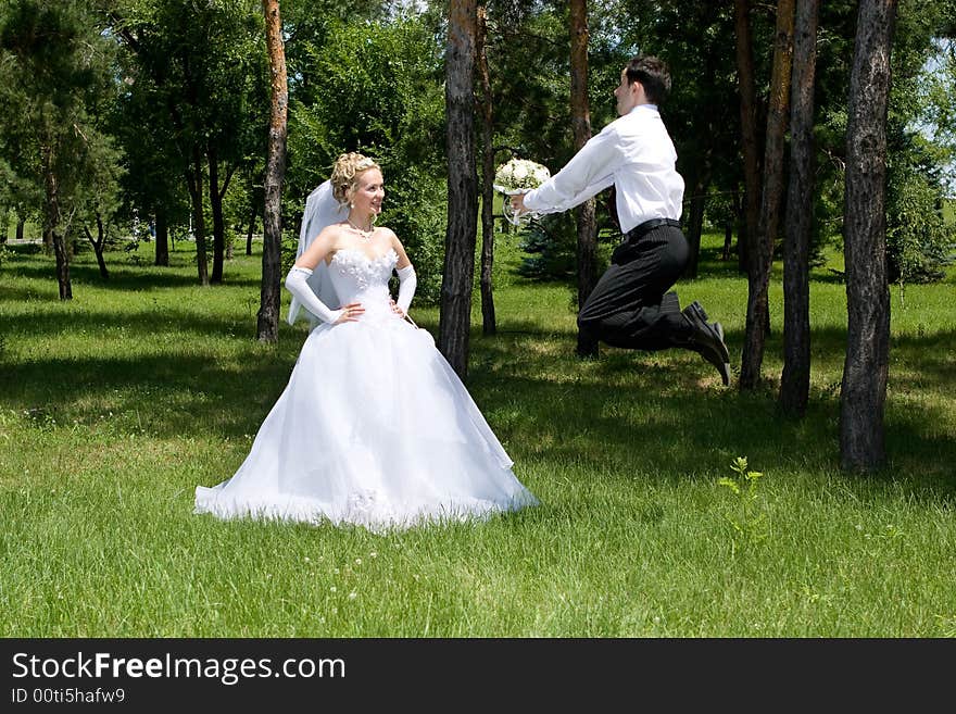 Groom with a wlower bouquet jumps near the bride. Groom with a wlower bouquet jumps near the bride