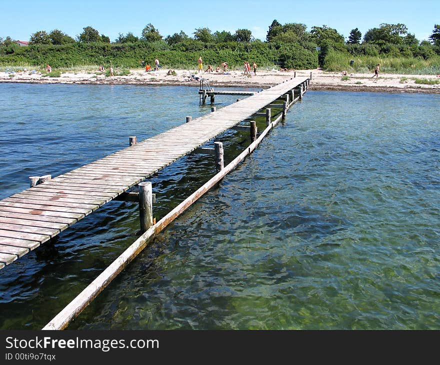 Beach fun - beach with a wooden pier jetty and clear sea water. Beach fun - beach with a wooden pier jetty and clear sea water