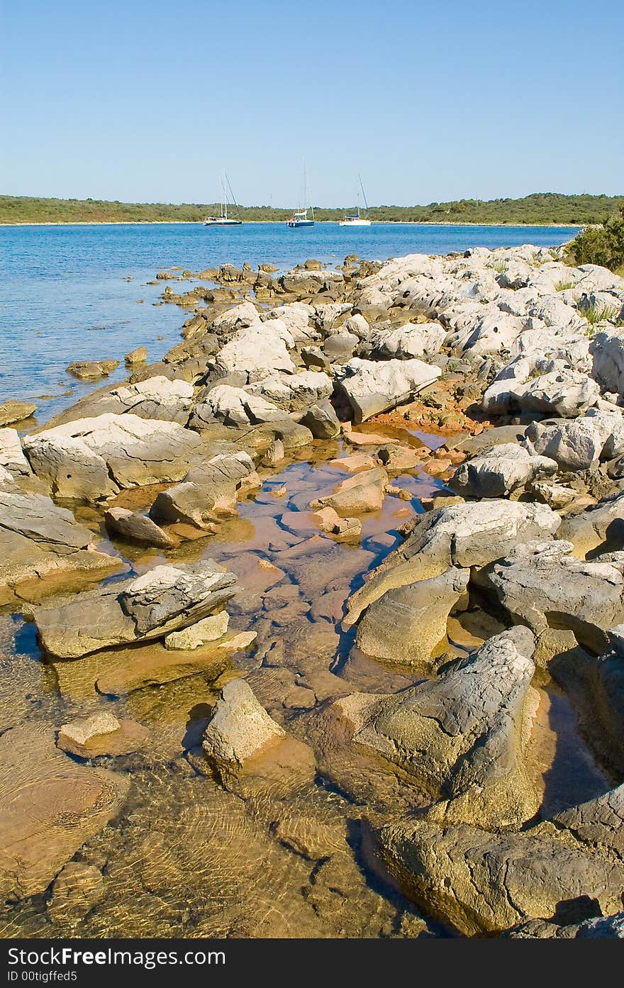 vertical stone coastline with thtree yachts view