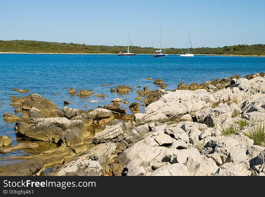 Gorizontal stone coastline with three yachts view. Gorizontal stone coastline with three yachts view