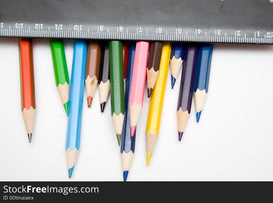 Multicolored pencils and black ruller on the whie isolated background. Multicolored pencils and black ruller on the whie isolated background