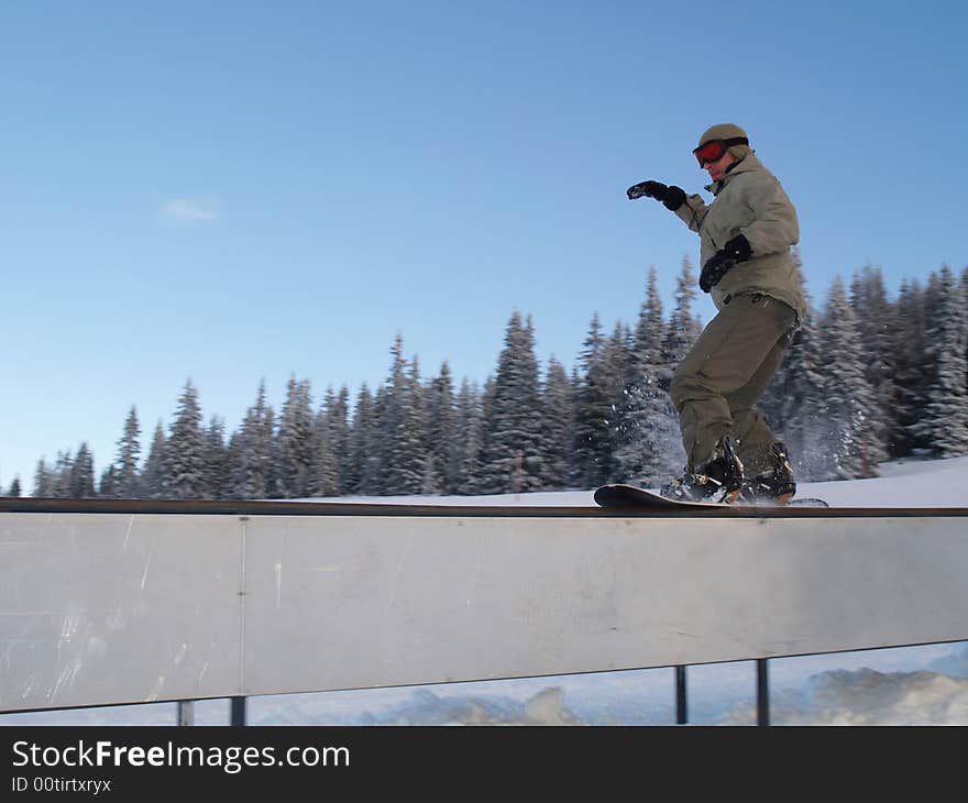 Freeride snowboarder sliding on rail.