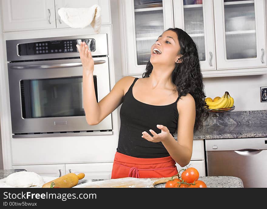 Young woman in kitchen tossing dough in the air. Young woman in kitchen tossing dough in the air