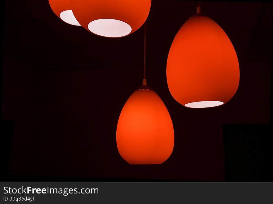 Four red modern lamps in a black room. Four red modern lamps in a black room