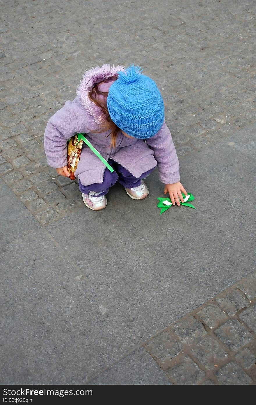 Child has found the bow torn away from her present package. Child has found the bow torn away from her present package